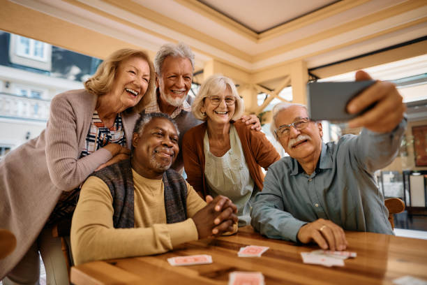 group of elderly individuals surrounding each other sitting at a table taking a picture together.